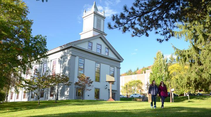 view of alumni hall with two students walking down the path away from the building